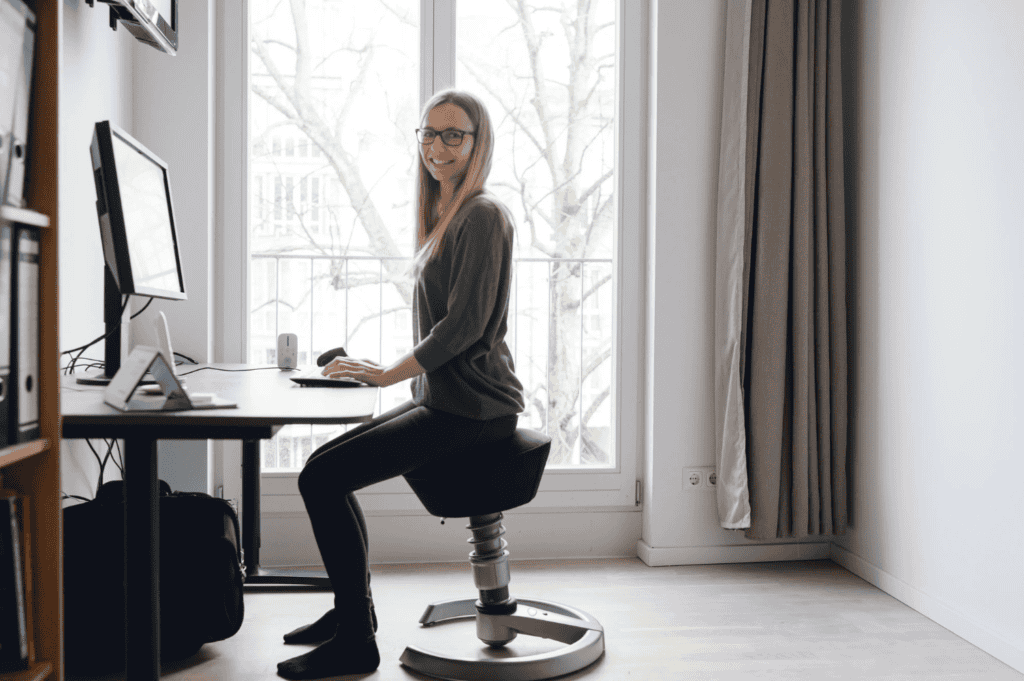 Eine Frau sitzt auf einem ergonomischen Stuhl vor einem Schreibtisch.